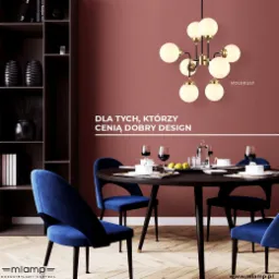 Lampa sufitowa w stylu molekularnym z kulistymi kloszami nad okrągłym stołem jadalnym z nakryciem i niebieskimi krzesłami w eleganckim wnętrzu.