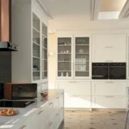 Jasna kuchnia w stylu klasycznym z białymi szafkami, przeszklonymi witrynami, marmurowym blatem i nowoczesnym okapem w kolorze miedzi, widoczne dwa piekarniki w zabudowie.