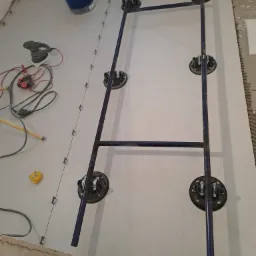 Układanie wielkoformatowych płytek podłogowych przy użyciu specjalistycznego stelaża z przyssawkami; widoczne narzędzia glazurnicze, poziomowanie krzyżykami dystansowymi.