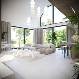 emwe studio architektury - Jasne, przestronne wnętrze z dużymi oknami wychodzącymi na zieleń, szary narożnik z poduszkami i pledem, białe stoliki kawowe, designerskie lampy wiszące i rośliny doniczkowe.