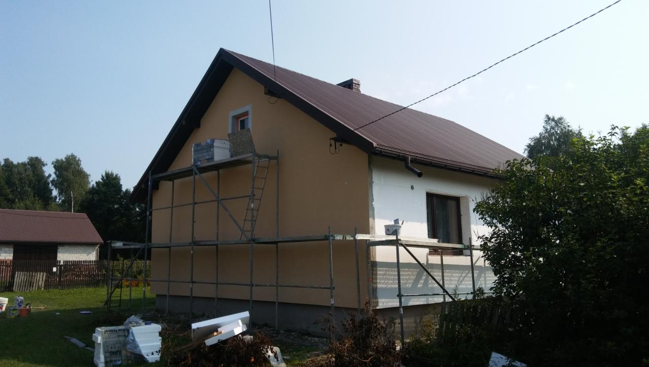 Dom w Częstochowie w trakcie ocieplania elewacji, widoczne rusztowania, częściowo otynkowana ściana i styropian do ocieplenia.