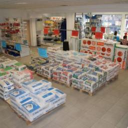 Budexpert - Wnętrze składu budowlanego z paletami worków zaprawy murarskiej Ixel MP 75L oraz materiałów ociepleniowych Terma Organika, widoczne regały z narzędziami i akcesoriami.