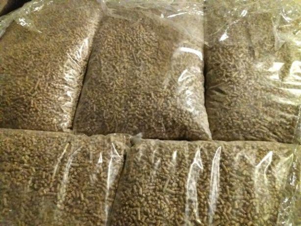 Foliowe worki wypełnione jasnobrązowym pelletem ułożone jeden na drugim, widoczne z bliska.