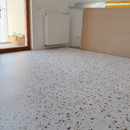 Tomasz Górski - Wykończona podłoga z terazzo w jasnym pomieszczeniu z balkonem, widoczne płyty gipsowe i poziomice opierające się o ścianę.