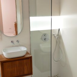 Tomasz Górski - Nowoczesna łazienka z kabiną prysznicową typu walk-in, umywalką nablatową na drewnianej szafce i podłogą w stylu lastryko.