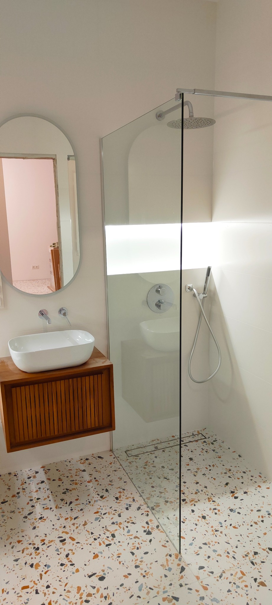 Nowoczesna łazienka z kabiną prysznicową typu walk-in, umywalką nablatową na drewnianej szafce i podłogą w stylu lastryko.