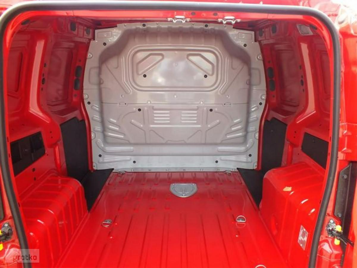 Wnętrze puste, czerwonej furgonetki dostawczej z metalową przegrodą i mocowaniami podłogowymi.