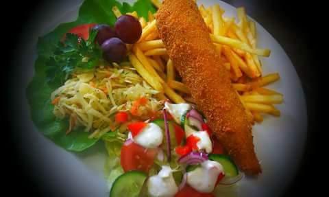 Kotlet panierowany z frytkami, surówką z kapusty i sałatką warzywną na talerzu, dekoracja z winogron.