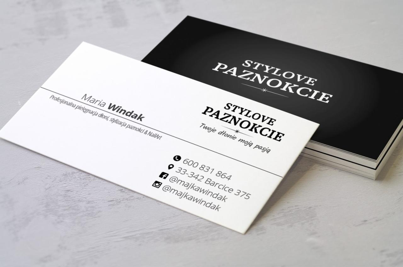 Stos wizytówek w kolorach czerni i bieli z danymi kontaktowymi salonu stylizacji paznokci, widoczne logo i nazwa firmy.