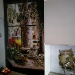 Panel szklany z motywem ziołowym nad blatem i zlewem w kuchni, widoczne butelki, słoiki z przyprawami i zioła, w tle okno z suszonymi ziołami.