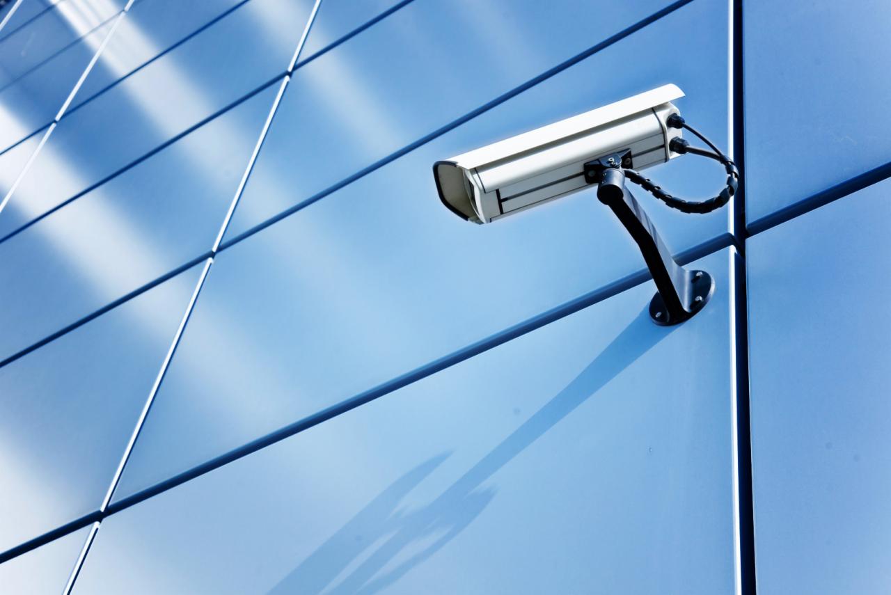 Zewnętrzna kamera monitoringu zamontowana na nowoczesnej, błękitnej elewacji budynku z paneli kompozytowych.