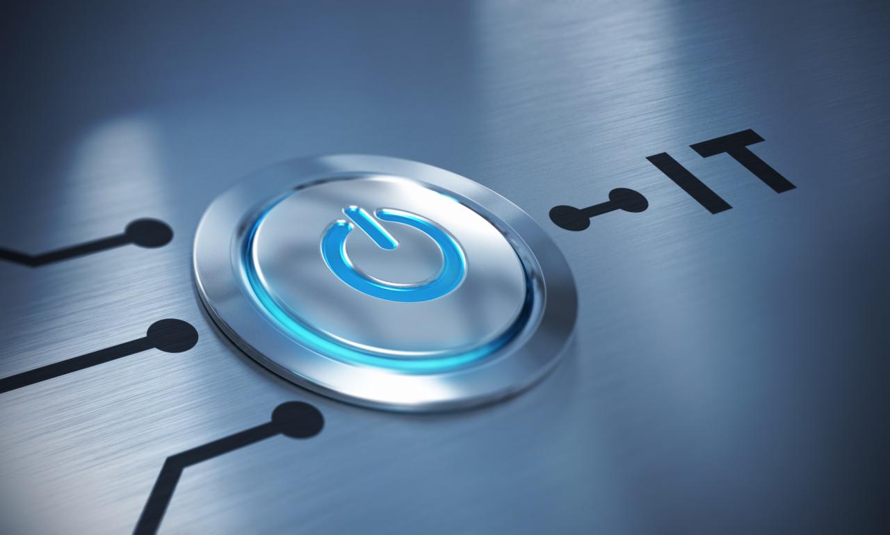 Podświetlony na niebiesko przycisk zasilania na metalowej powierzchni z napisem 'IT' i schematycznymi liniami obwodu.