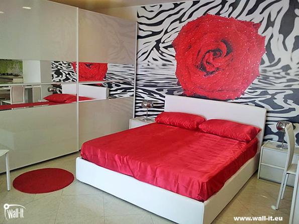 Sypialnia z białymi meblami i łóżkiem z czerwoną pościelą, na ścianie fototapeta z motywem zebry i dużą czerwoną różą.