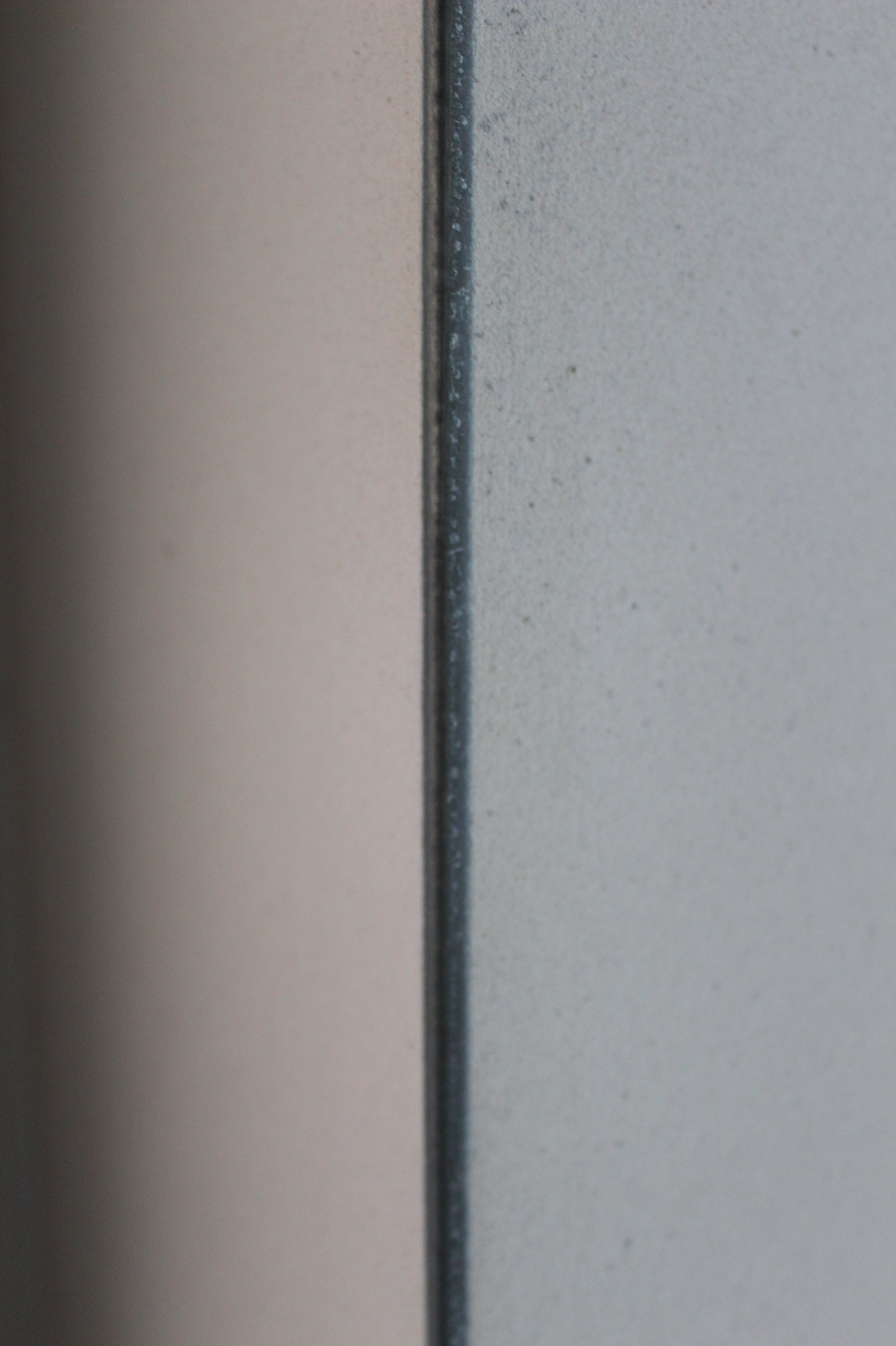 Fragment ściany po nałożeniu tynku maszynowego, widoczna struktura i połączenie dwóch powierzchni o różnej fakturze i kolorze.