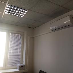 Cool-Install - Biała klimatyzacja Kaisai Fly zamontowana na ścianie w biurze, widoczna podwieszana sufitowa instalacja oświetleniowa i tablica suchościeralna z notatkami.