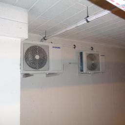 Cool-Install - Dwa klimatyzatory marki Hyundai zamontowane na ścianie w pomieszczeniu z surowym, białym wykończeniem; widoczne rury instalacyjne pod sufitem.