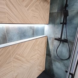 STYLOWE WNĘTRZE WARSZAWA MARIUSZ BIERNACKI - Nowoczesna kabina prysznicowa z geometrycznymi płytkami w odcieniach beżu i szarości, czarną armaturą i odpływem liniowym. Wnęka z podświetleniem.
