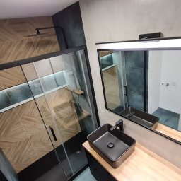 STYLOWE WNĘTRZE WARSZAWA MARIUSZ BIERNACKI - Nowoczesna łazienka z kabiną prysznicową typu walk-in, umywalką nablatową i dużym lustrem z oświetleniem LED. Uwagę zwracają płytki imitujące drewno i czarne akcenty.