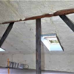 Termoprof Dawid Osiński - Poddasze po ociepleniu pianką, widoczne drewniane krokwie i okno dachowe, na podłodze drabina aluminiowa
