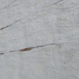 Poddasze z widocznymi belkami drewnianymi pokryte grubą warstwą białej, spienionej izolacji termicznej.