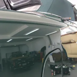 Błyszczący, zielony lakier klasycznego kabrioletu po renowacji w warsztacie w Hornówku, z widocznym odbiciem wnętrza warsztatu i zaparkowanego innego auta. Otwarte drzwi ukazują beżową tapicerkę.