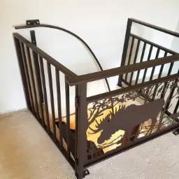 Metalowa balustrada schodowa w kolorze brązowym z laserowo wycinanym motywem łosia i drzew w lesie, zamontowana na schodach wewnątrz budynku.