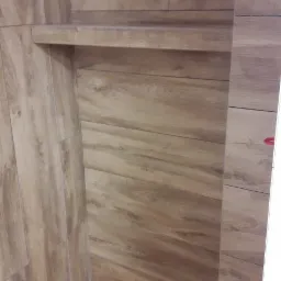 Półka wnękowa wykończona płytkami imitującymi drewno, z widocznymi fugami i detalami tekstury drewna.