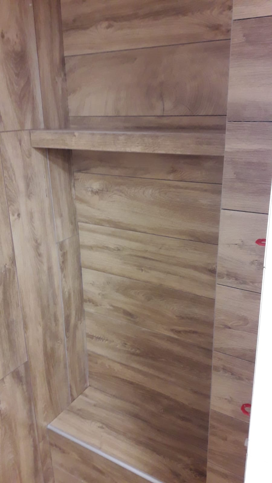 Półka wnękowa wykończona płytkami imitującymi drewno, z widocznymi fugami i detalami tekstury drewna.