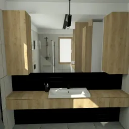 Nowoczesna łazienka z drewnianymi szafkami, czarnym panelem nad blatem, białym zlewem i grzejnikiem drabinkowym z ręcznikiem, oświetlona naturalnym światłem z okna z roślinami.