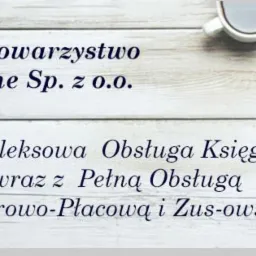 Biurko z kalkulatorem, okularami, notatnikiem i filiżanką kawy, na tle drewnianej powierzchni. Widoczny branding firmy oferującej kompleksową obsługę finansową i kadrową.