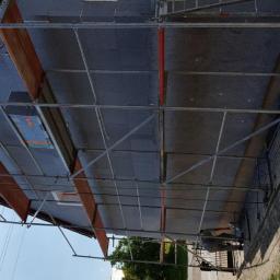 zaklad ogólnobudowlany Karbud - Dom w trakcie ocieplania styropianem grafitowym, widoczne rusztowanie i pracownik przy elewacji.
