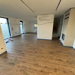 Lasmet - Pokój w trakcie przygotowań do malowania: zabezpieczone folią okna, ściany i klimatyzator, drewnopodobna podłoga, perforowany sufit podwieszany.