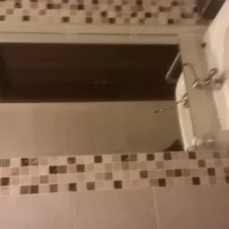 Umywalka w łazience z mozaiką na ścianie i lustrem odbijającym sufit.