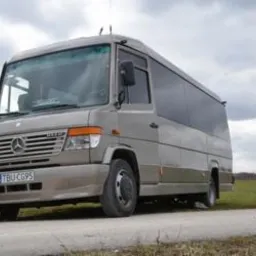 Beżowy mikrobus Mercedes z czarnymi szybami, zaparkowany na poboczu polnej drogi, tablica rejestracyjna TBU CG95.