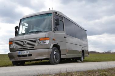 Beżowy mikrobus Mercedes z czarnymi szybami, zaparkowany na poboczu polnej drogi, tablica rejestracyjna TBU CG95.