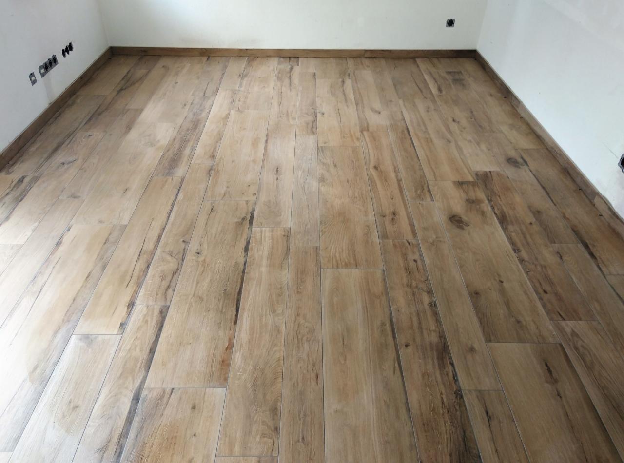 Ułożona podłoga z paneli imitujących drewno w nowym pomieszczeniu, widoczne gniazdka elektryczne i listwy przypodłogowe.