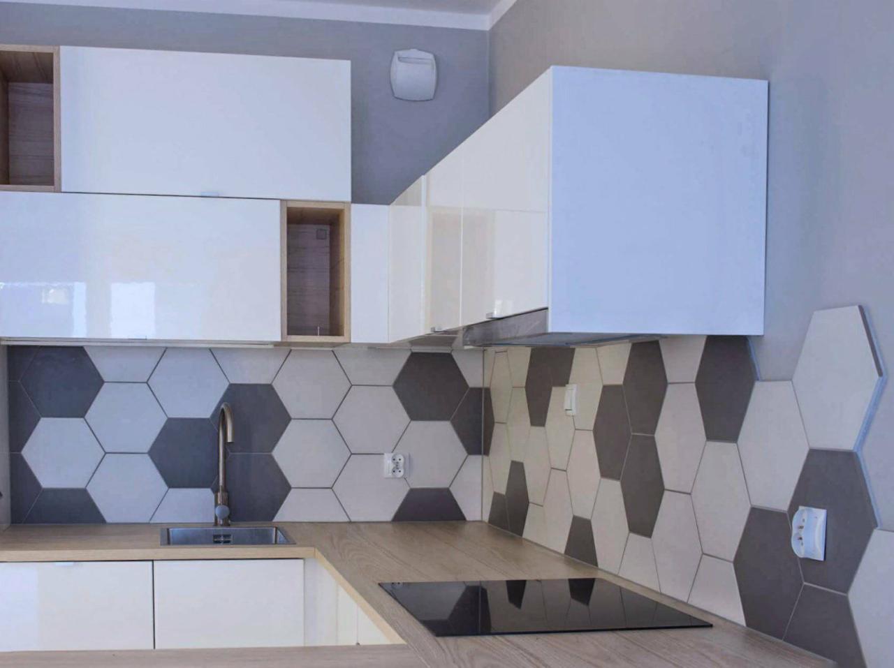 Nowoczesna kuchnia z białymi szafkami i heksagonalnymi płytkami w odcieniach szarości, drewniany blat i płyta indukcyjna.