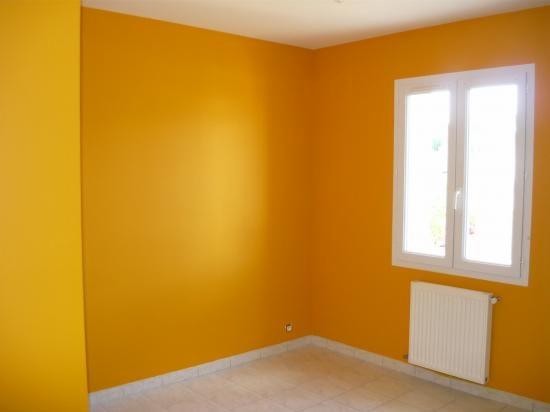 Pomarańczowy pokój po malowaniu ścian, widoczny biały grzejnik pod oknem i jasna podłoga z płytek.