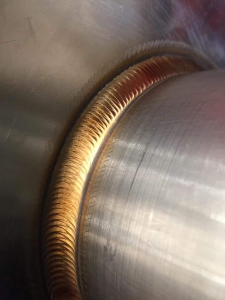 Precyzyjne spoiny obwodowe na rurze ze stali nierdzewnej, widoczne delikatne ślady obróbki cieplnej i charakterystyczny wzór zgrzewu.