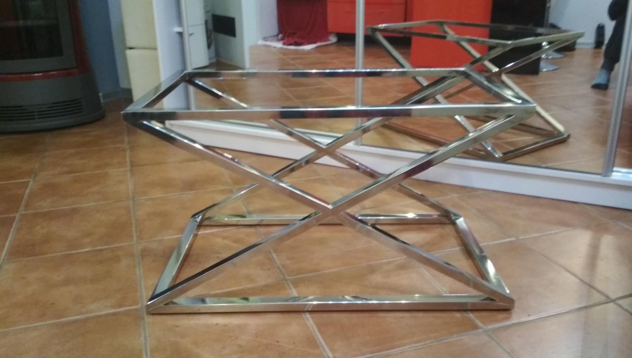 Metalowa konstrukcja stolika kawowego ze stali nierdzewnej z Kielc, spawana z profili o kwadratowym przekroju, na brązowych płytkach podłogowych.