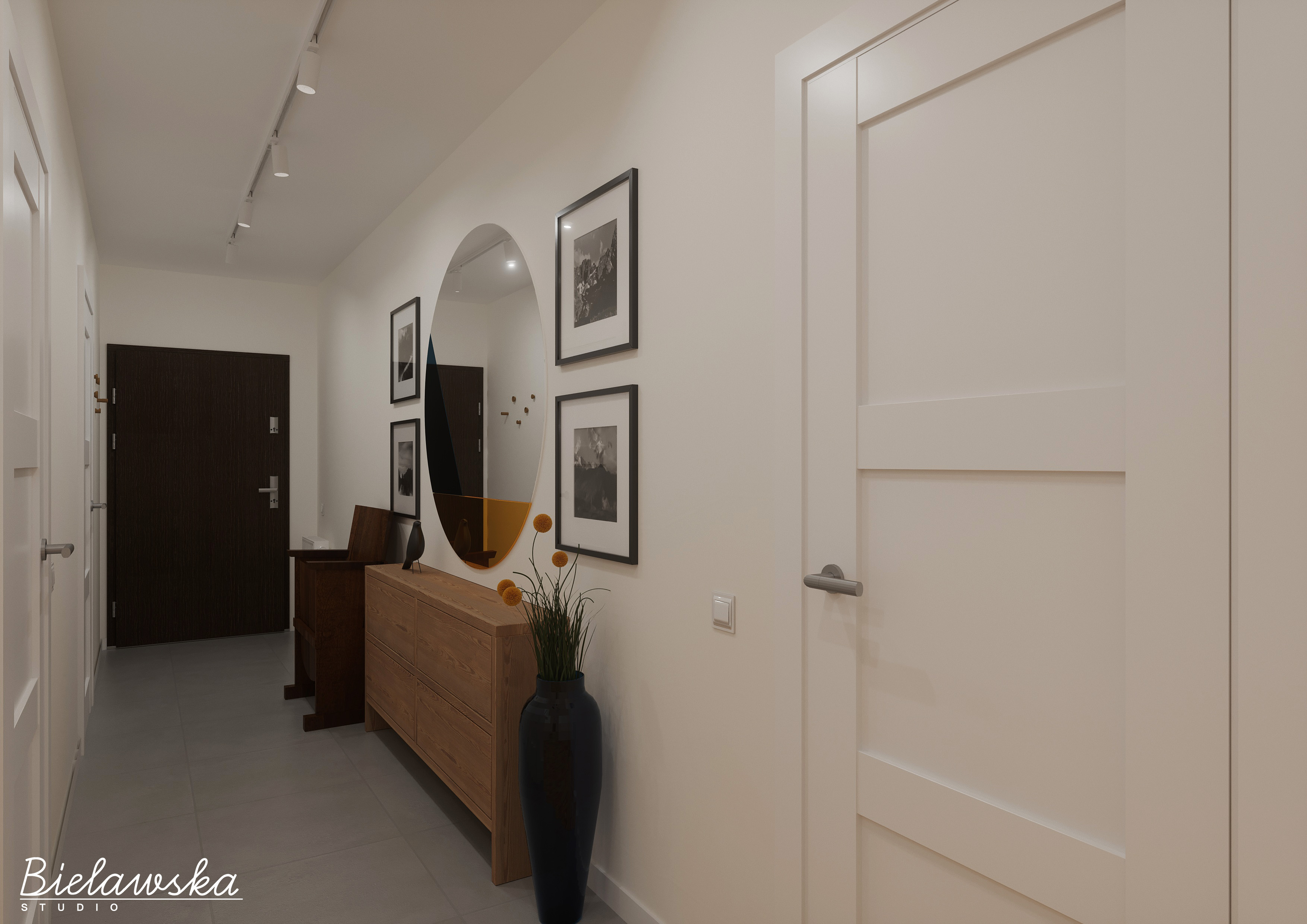 Nowoczesny przedpokój z drewnianą komodą, okrągłym lustrem z pomarańczowym akcentem i czarnym wazonem z kwiatami, oświetlony reflektorami szynowymi.