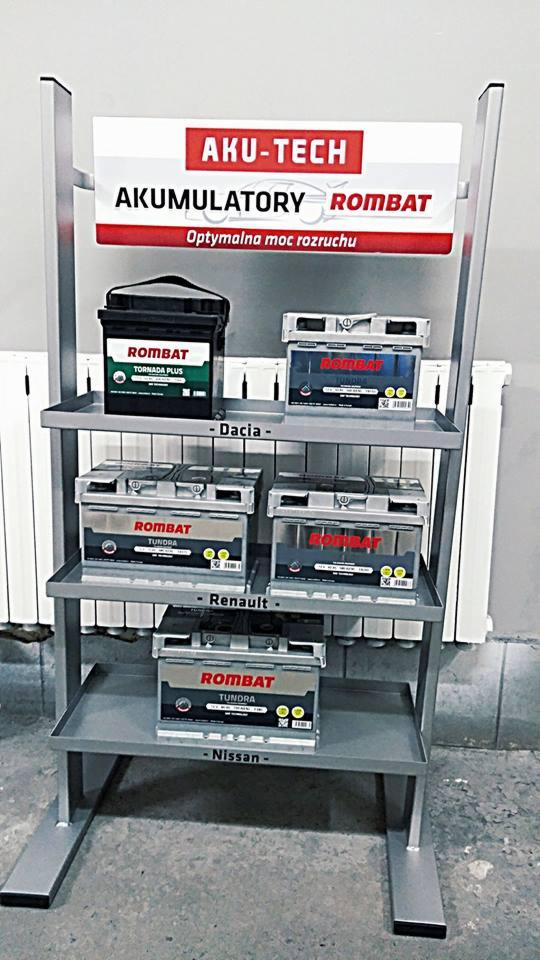 Ekspozycja akumulatorów samochodowych Rombat na metalowym regale z logo Aku-Tech, modele Tornado Plus i Tundra, z oznaczeniami marek samochodów Dacia, Renault i Nissan.