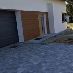 Nowoczesny dom jednorodzinny z elewacją w kolorze bieli i drewna, szara kostka brukowa na podjeździe, widok z boku.