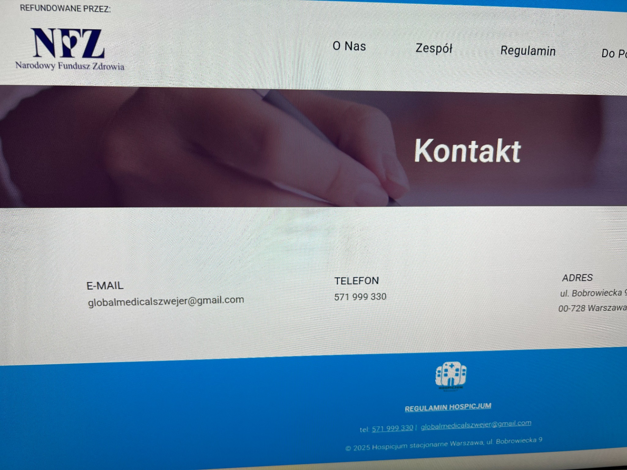 Strona internetowa hospicjum z informacjami kontaktowymi: adres, telefon, e-mail. Widoczne logo NFZ. Zakładka 'Kontakt' na stronie.