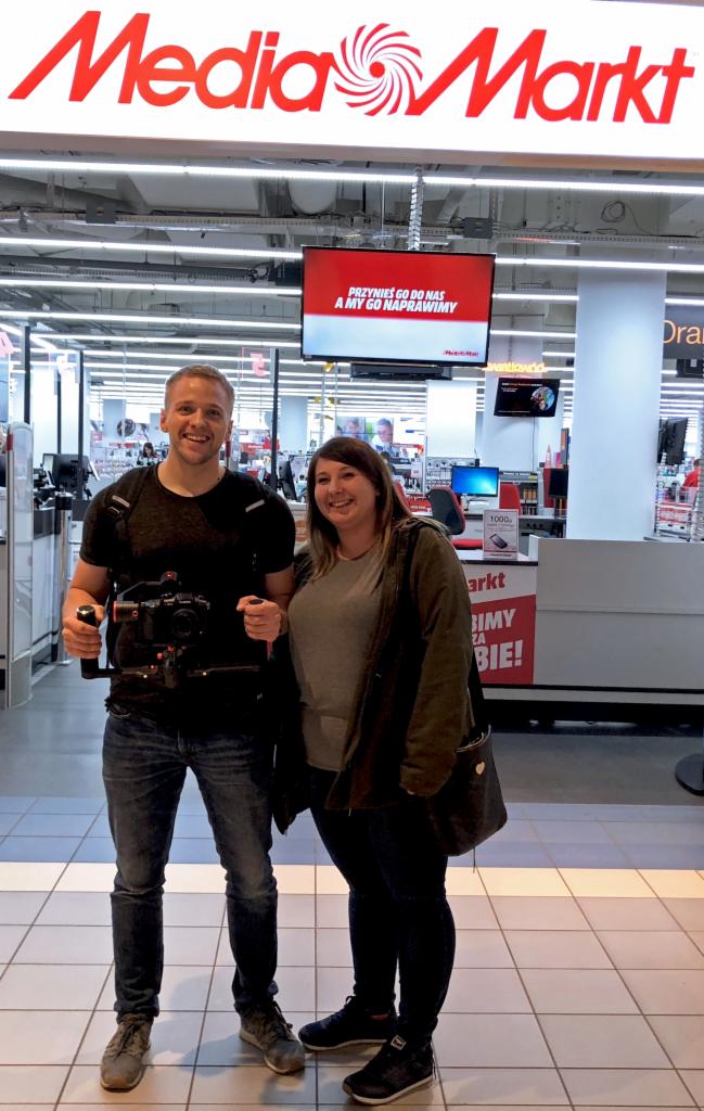 Ekipa filmowa z kamerą stabilizującą w sklepie Media Markt, prawdopodobnie realizująca nagranie promocyjne.