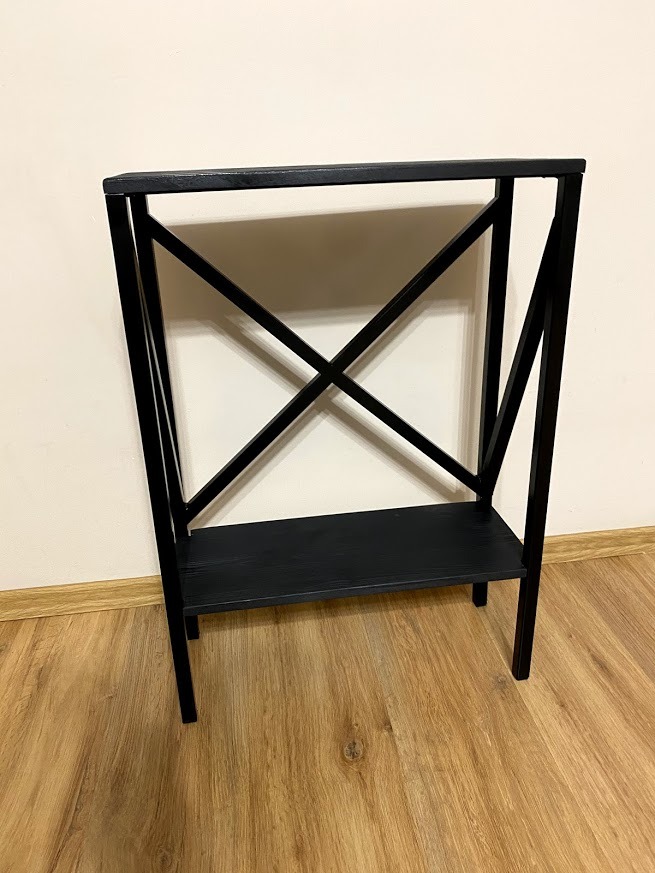 Czarny, metalowy regał z dwoma półkami i krzyżowymi wzmocnieniami bocznymi, stojący na panelach podłogowych.