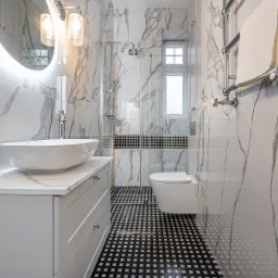 Nowoczesna łazienka z marmurowymi płytkami, owalną umywalką nablatową, podświetlanym lustrem i czarno-białą mozaiką na podłodze.