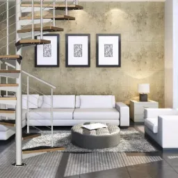 Nowoczesne wnętrze z białą spiralną konstrukcją schodów z drewnianymi stopniami, na tle jasnej ściany z trzema obrazami, białą sofą i fotelem.