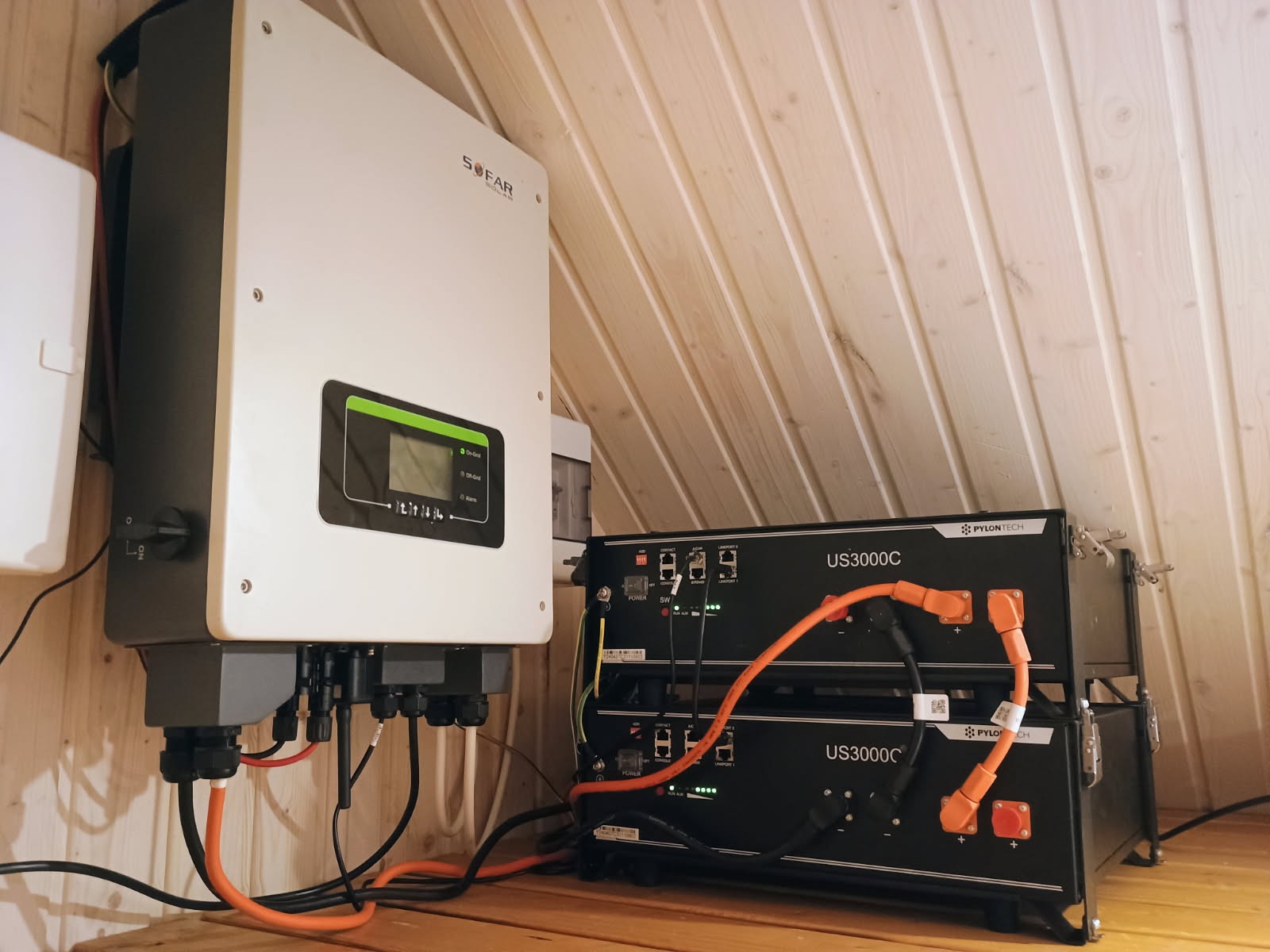 Instalacja domowa: Inwerter SOFAR i dwa akumulatory PYLONTECH US3000C na drewnianej podłodze i pod drewnianym skośnym sufitem.