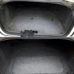Porównanie bagażnika samochodowego przed i po czyszczeniu, widoczna różnica w odcieniu szarości wykładziny.